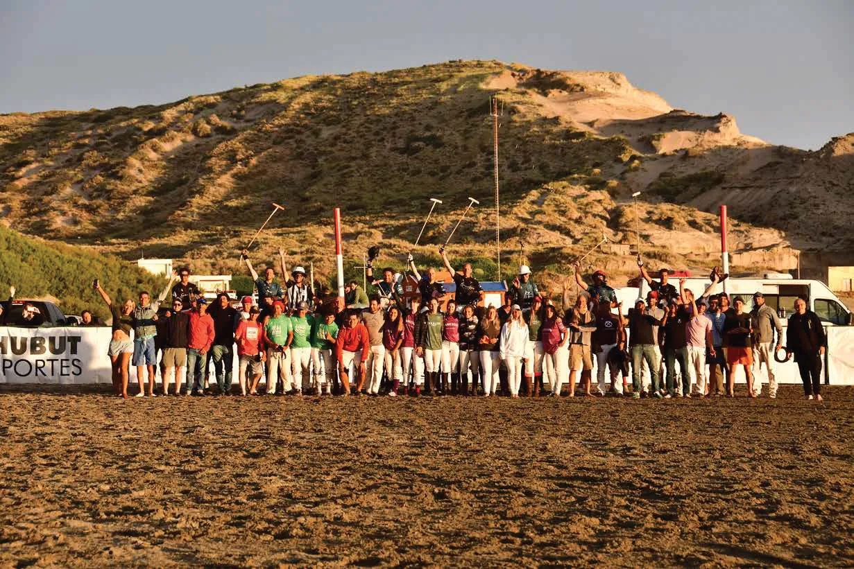 Equipo de beach polo posando en la playa de Puerto Pirámides al atardecer, con los médanos de fondo