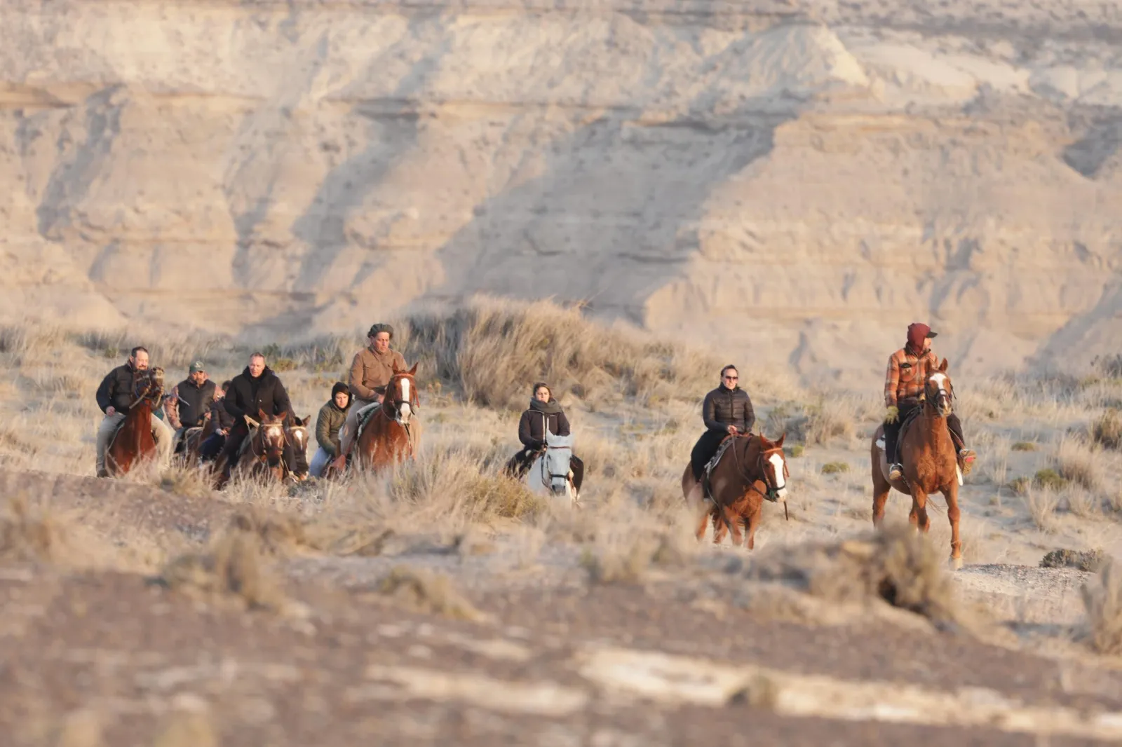 Grupo de jinetes cruzando la estepa con los acantilados de fondo